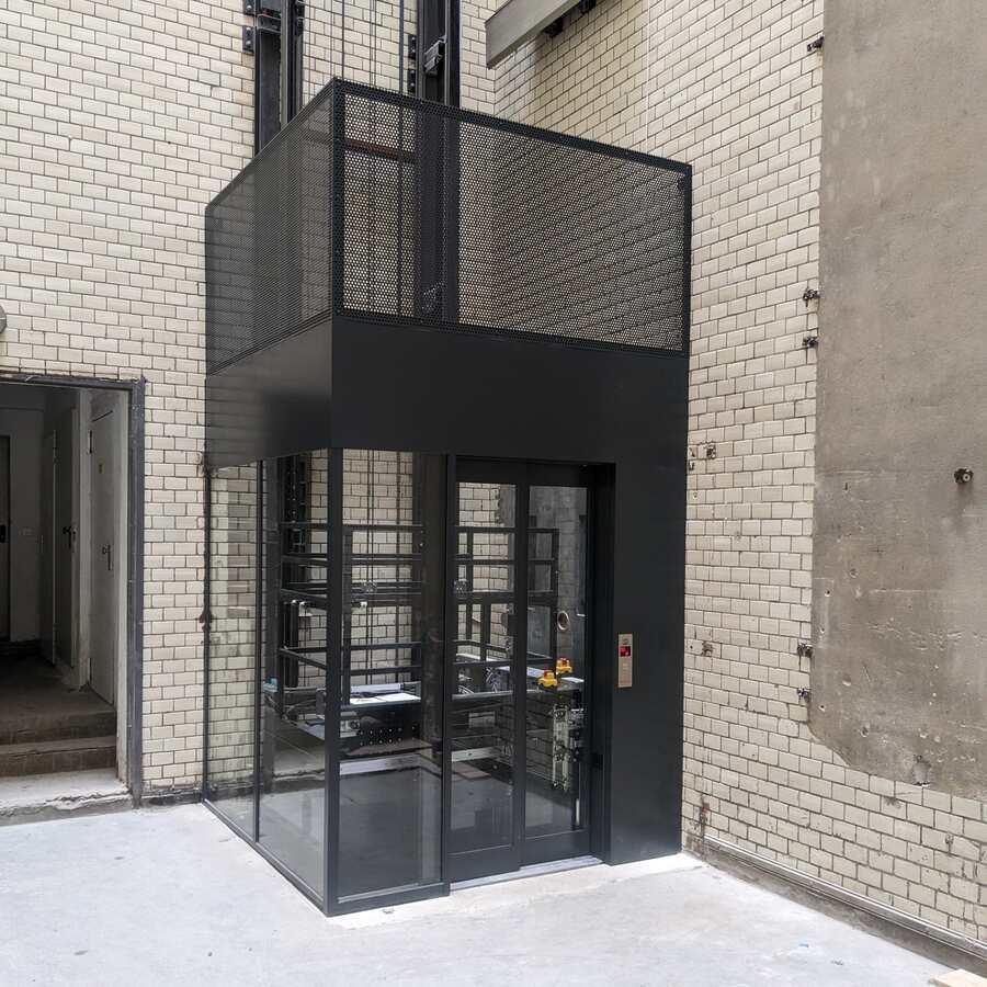 Maßgefertigte Aufzugseinhausung aus Stahl im Innenhof eines Gebäudes in Berlin